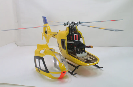 Yellow RC helicopter with detached canopy showing internal components