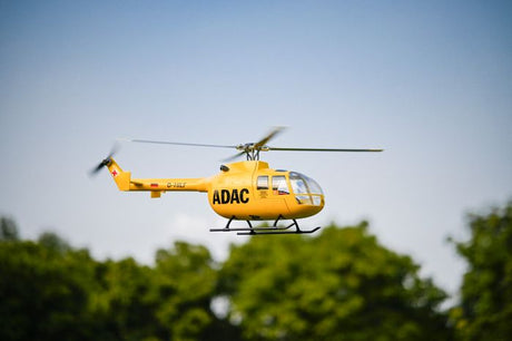 Large RC helicopter for adults flying against a clear sky, showcasing scale realism and performance