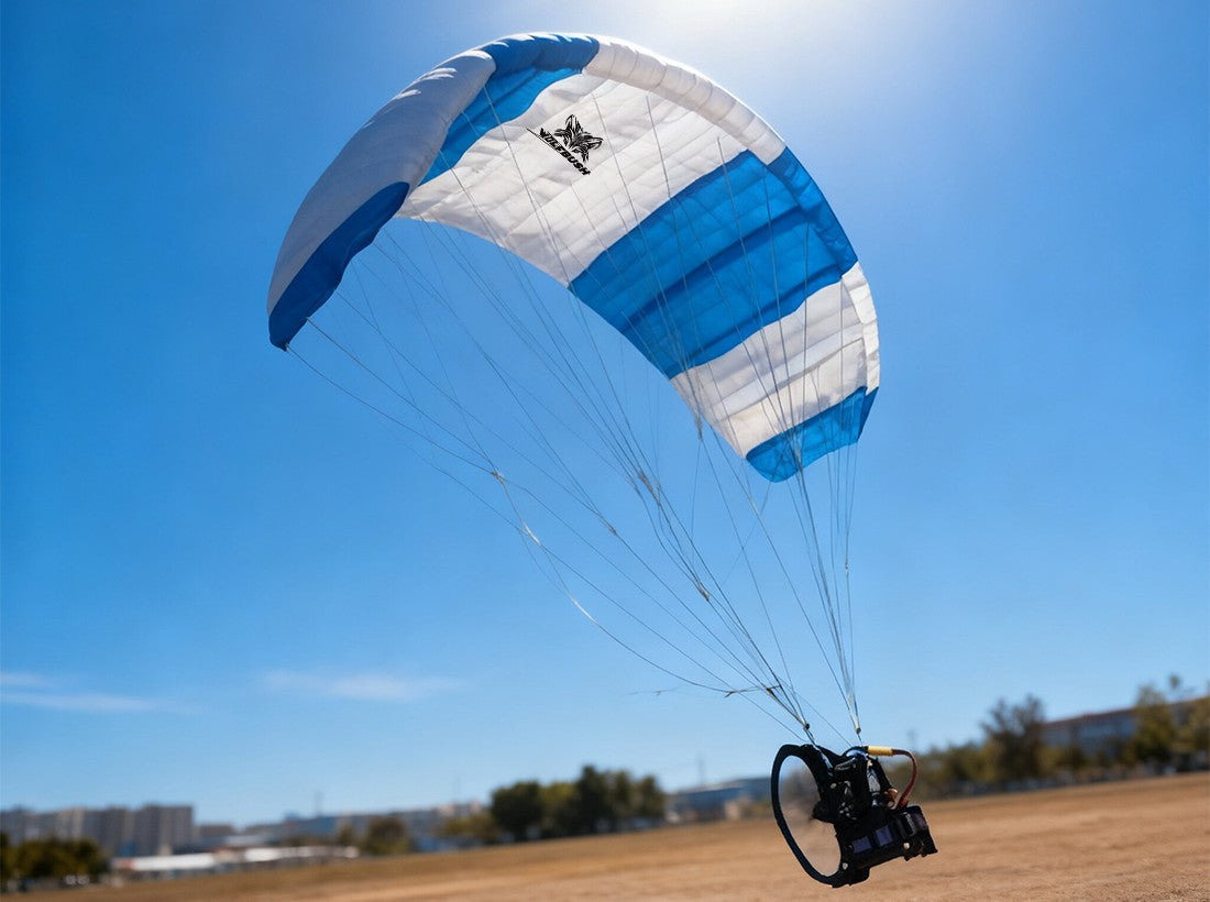 Blue and white RC paraglider soaring in clear blue sky.